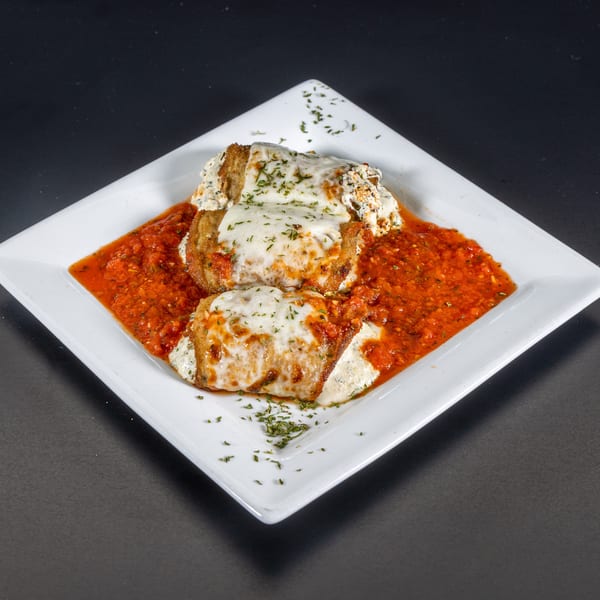 Two cheese-covered eggplant parmesan rolls in a rich red sauce, garnished with parsley on a white plate.